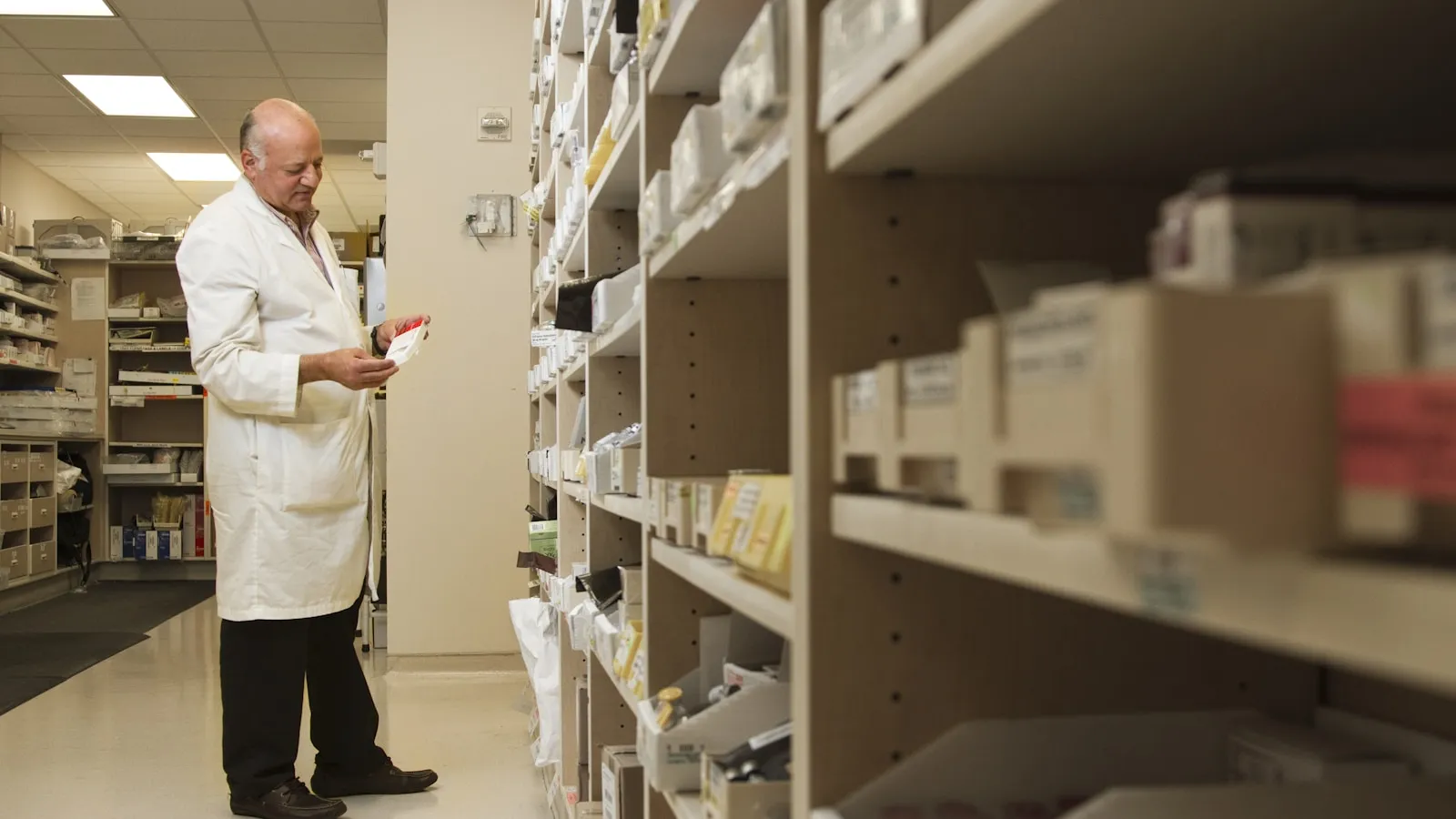 Apotheekmedewerker pakt een doosje van een schap in een apotheek.