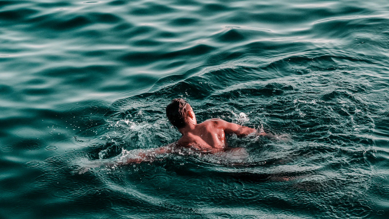 Man zwemt in open water tijdens daglicht.