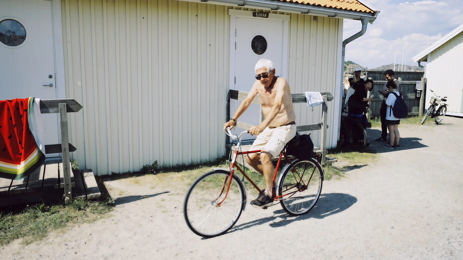 Oudere man fietst langs strandhuisjes in het daglicht.