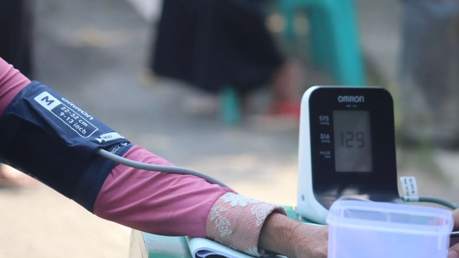 Een arm met een manchet aangesloten op een digitale bloeddrukmeter thuis.