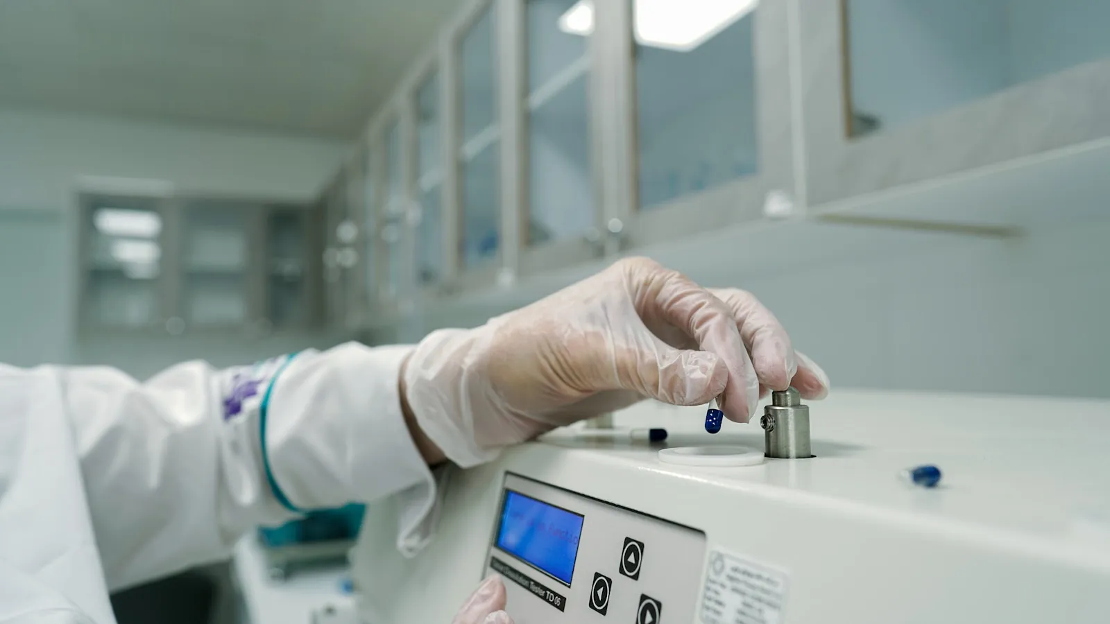 Laborant met handschoenen plaatst een monster in een laboratoriumapparaat.