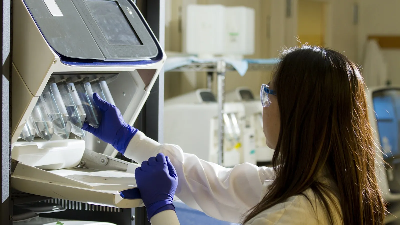 Laborant plaatst buisjes in een analyseapparaat in een laboratorium.