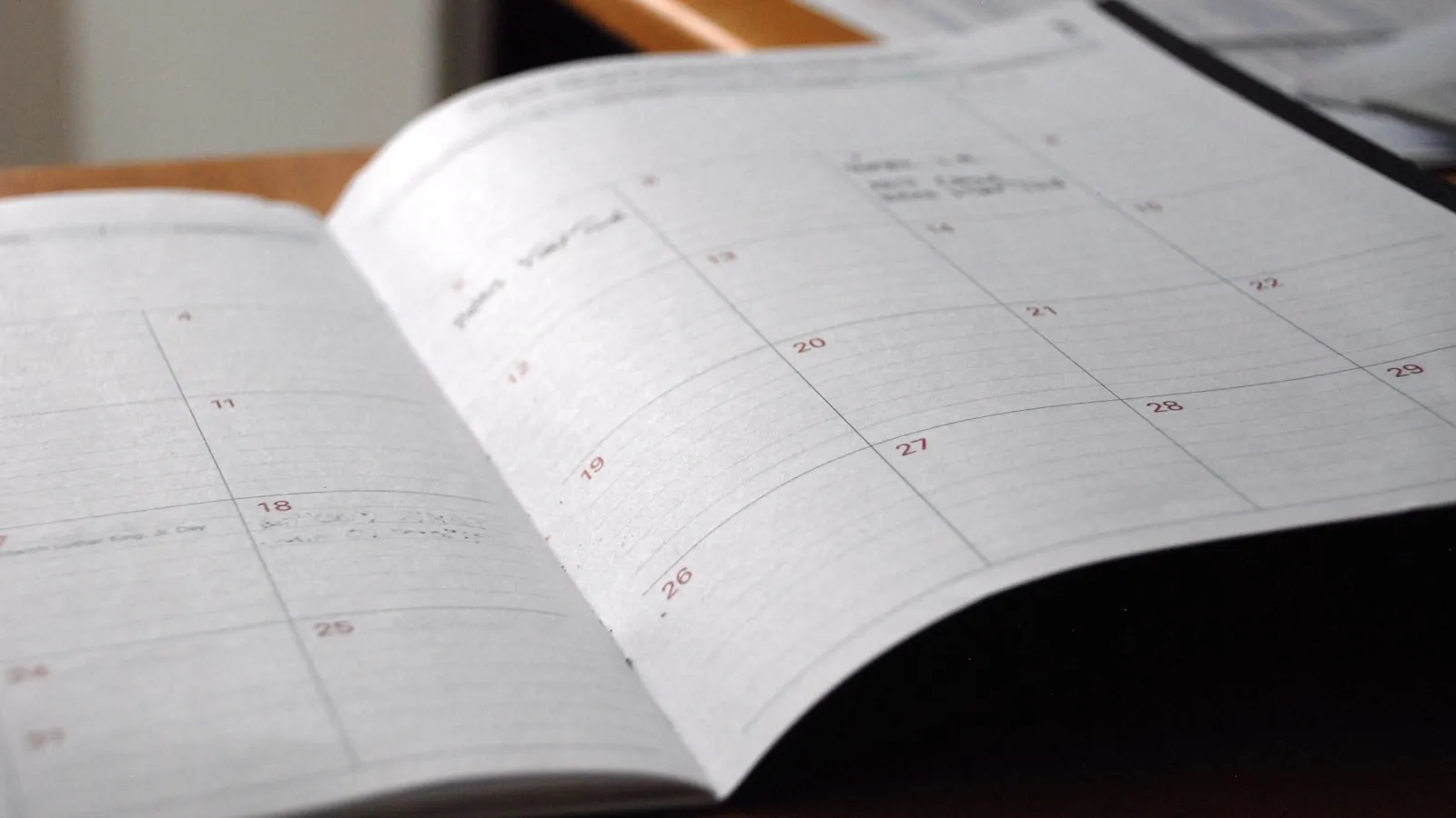 Opengeslagen maandplanner op een houten bureau.