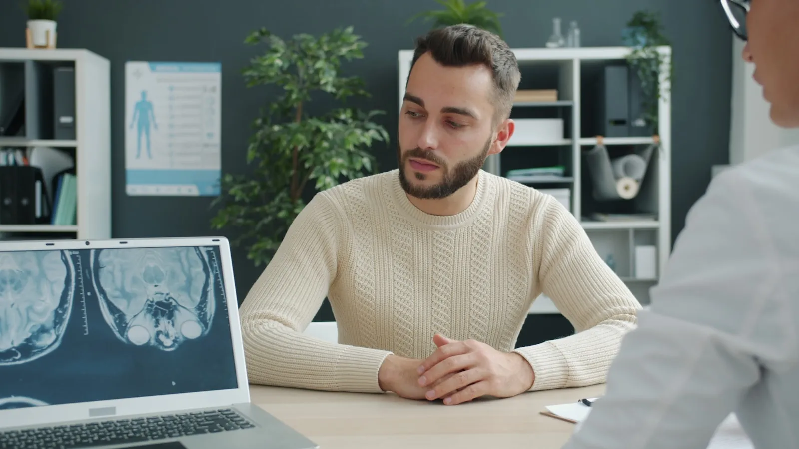 Man in gesprek met een arts aan een bureau in een spreekkamer.